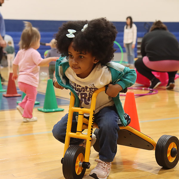 A girl on a tricycle.